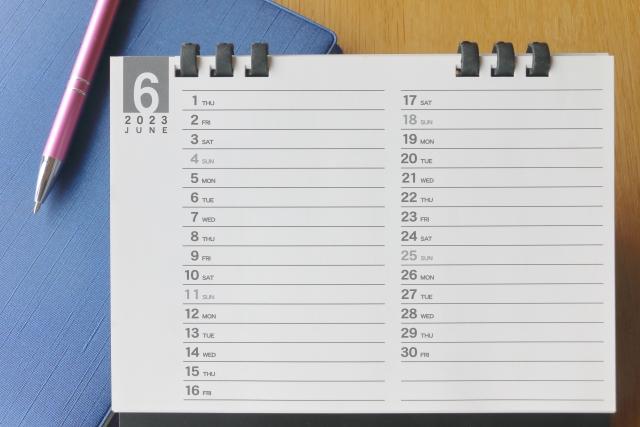 6月のカレンダーとノート、ボールペンが机に置いてあります。